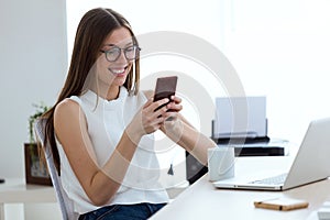 Business young woman using her mobile phone in the office.