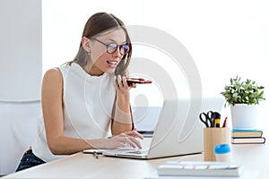 Business young woman working with her mobile phone and laptop in the office.