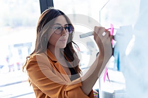 Business young woman working on white board with post it stickers in the office