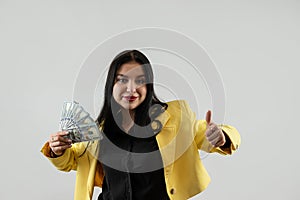business young woman in yellow suit with dollars money isolated on grey background
