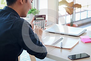 Businessman or accountant Asian young man holding calculator to calculate financial data, cost and budget