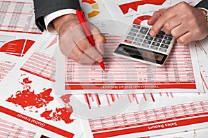 Businessman accountant using calculator for calculating finance on desk office. Business financial accounting concept Red reports