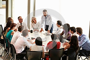 Businessman Addressing Meeting Around Boardroom Table