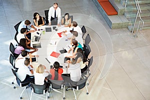 Businessman Addressing Meeting Around Boardroom Table