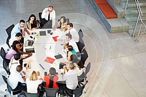 Businessman Addressing Meeting Around Boardroom Table