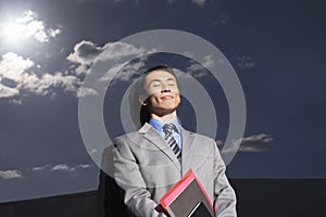 Businessman Against Reflective Wall With Eyes Closed