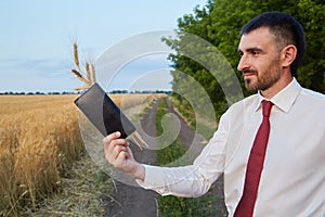 Businessman agronomist farmer in the field holds a wallet with spikelets of wheat