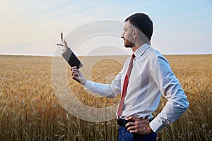 Businessman agronomist farmer in the field holds a wallet with spikelets of wheat