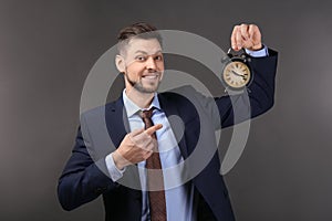 Businessman with alarm clock on dark background. Time management concept