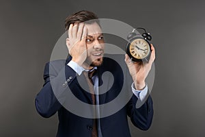 Businessman with alarm clock on dark background. Time management concept