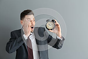 Businessman with alarm clock on gray background. Time management concept