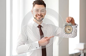 Businessman with alarm clock in office. Time management concept