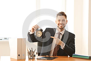 Businessman with alarm clock at table in office. Time management concept