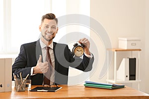 Businessman with alarm clock at table in office. Time management concept