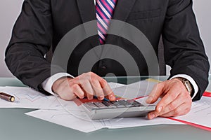 Businessman analysing income charts and graphs with calculator.