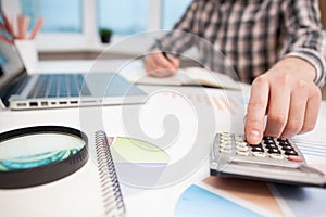 Businessman analyzing business graphs with magnifying glass