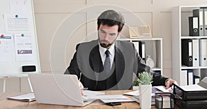 Businessman analyzing document and writing notes at desk