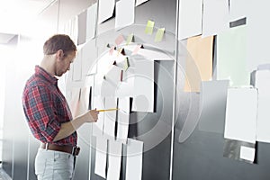 Businessman analyzing documents on wall at creative office