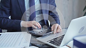 Businessman analyzing financial data on laptop and calculator. Close-up of a professional auditor working on financial