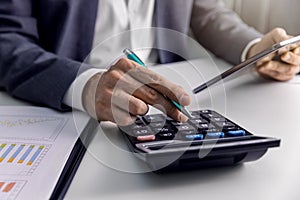 Businessman analyzing financial graphs and charts in office with calculator and digital tablet. business reports