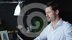 Businessman analyzing financial reports at workplace. Man working on laptop