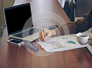 Businessman analyzing graph document and holding coffee in office