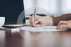 Businessman analyzing graph document with laptop and coffee in office