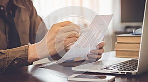 Businessman analyzing graph document with laptop and coffee in office vintage tone