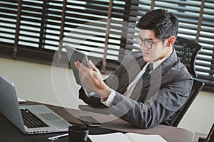 Businessman analyzing investment charts with tablet and laptop.