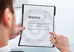 Businessman analyzing invoice at office desk