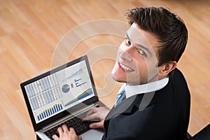 Businessman Analyzing Statistical Data On Laptop