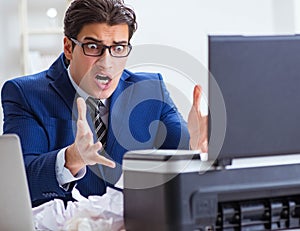 Businessman angry at copying machine jamming papers photo