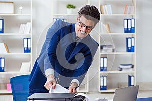 The businessman angry at copying machine jamming papers photo