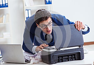 Businessman angry at copying machine jamming papers photo