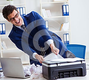 Businessman angry at copying machine jamming papers photo