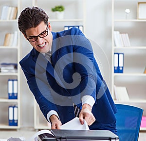 Businessman angry at copying machine jamming papers photo