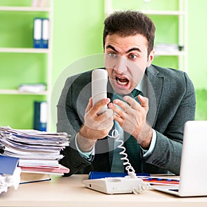 Businessman angry with excessive work sitting in the office