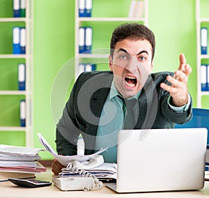 Businessman angry with excessive work sitting in the office