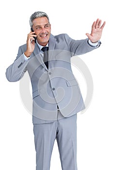 Businessman answering phone and waving