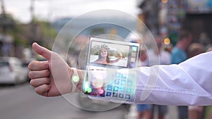 Businessman answers the pretty wife who smiles and waves hand from the phone that appears in hologram futuristic clock