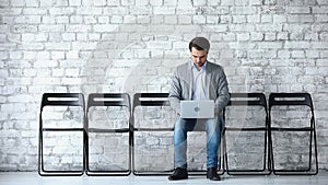 Businessman applicant using laptop sit on chair in waiting room