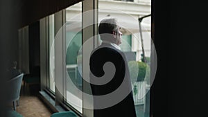 businessman approaches panoramic office window