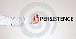 Businessman arm with hand as a clenched fist points towards the word persistence