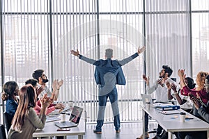 Businessman with arms up celebrating his victory with his collegues applauding