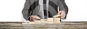 Businessman arranging wooden pegs into a staircase like structure