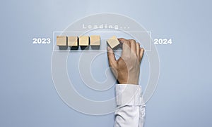 Businessman assembly wooden block in progress bar for loading new year 2023 to 2024 concept