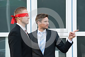 Businessman Assisting Blindfolded Partner