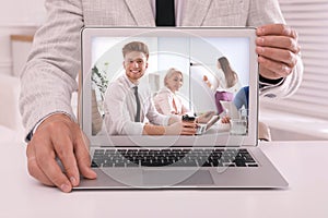 Businessman attending online video conference via laptop at table in office, closeup