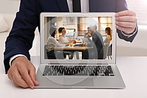 Businessman attending online video conference via modern laptop at table in office