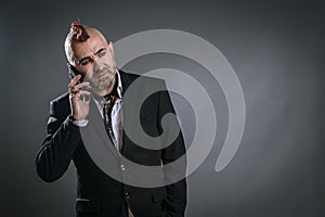 businessman attending to mobile with punky style in studio shot